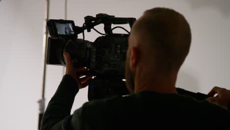 Close-Up-Of-Male-Film-Camera-Operator-Focusing-Camera-Using-Monitor-Shooting-Movie-Or-Video-In-Studio